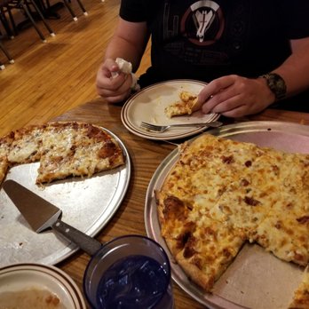 Boondock's Pizza - a man eating a slice of pizza - Pizza Near Me - Bellevue, Michigan