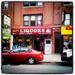 a red car parked in front of a liquor shop a red car parked in front of a liquor shop