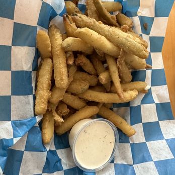 Frog Rock Tavern - Fried pickles - Fried fish strips served in a basket lined with blue and white checkered paper, accompanied by a cup of creamy dipping sauce. - New American Near Me - Meredith, New Hampshire