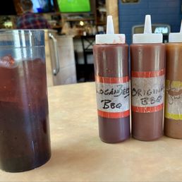 Assorted barbecue sauces and a glass of loganberry.
