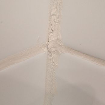 Jesse & Bro’s Construction - The image depicts a drywall corner where joint compound has been applied but appears uneven and poorly finished. Visible cracks and rough patches are present along the joint, indicating possible need for further sanding or finishing work. The focus is on the corner seam, with no additional context or surrounding wall details visible. - General Contractors Near Me - Oxnard, California