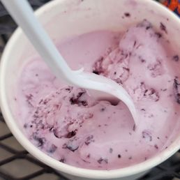 This is a half eaten single scoop of huckleberry ice cream.