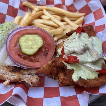 Five Points Cafe - Parmesan Crusted Chicken Sandwich. Pretty good, just a handheld mess to hold. - A chicken sandwich with lettuce, tomato, onion, and pickles, served with French fries on a checkered paper-lined tray. - Burgers Near Me - Sayville, New York