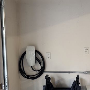 Comletric - Ev charger inside the garage - An electric vehicle charging station is installed on a plain wall inside a garage, with a black charging cable coiled around the charger. - Electricians Near Me - Concord, California