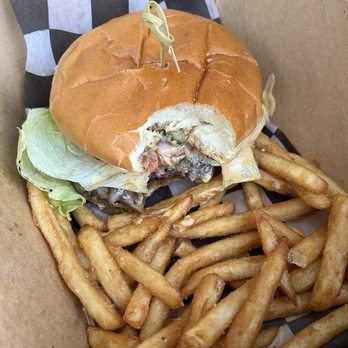 The Ranch Hand - Smash burger (fries)- 15$, service fee- 30c, cali tax- 1.24$ - A burger with lettuce, cheese, and meat is partially eaten, served with French fries in a paper-lined container. - Food Trucks Near Me - Chico, California