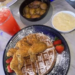 Chicken and waffles with a side of grits and potatoes. Drink is a flop made with lemonade and  fruit punch