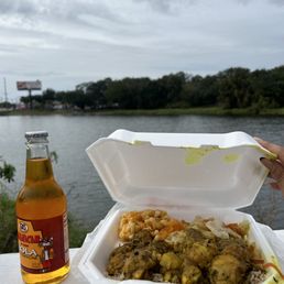 A Kola champagne, curry chicken, rice and peas, steamed cabbage, a water view