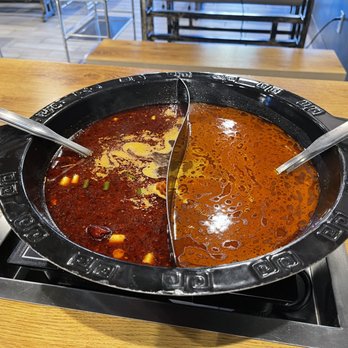 Potwhale - A Chinese hotpot with two different broths, one spicy and one mild, served in a black divided pot on a wooden table. - Hot Pot Near Me - Tucson, Arizona