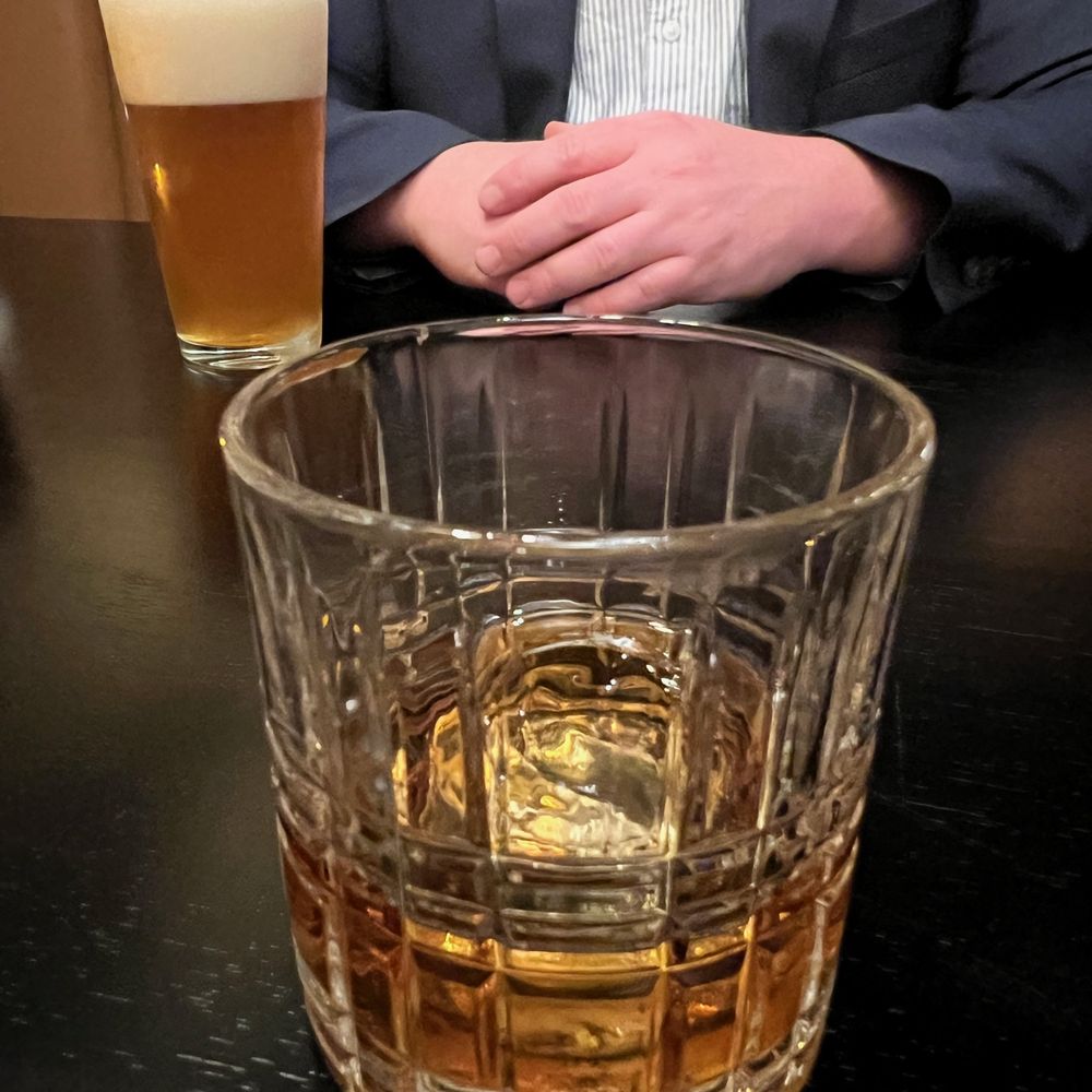 Beef + Bourbon Chophouse - a man sitting at a table with a glass of beer - Steakhouses Near Me - Bettendorf, Iowa