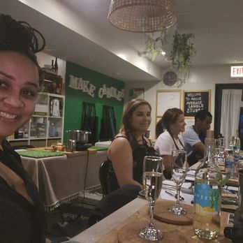 Above Average Candle Studio - People sit at a table in a candle-making studio, with supplies and drinks visible, and a woman smiling at the camera. - Candle Stores Near Me - Chicago, Illinois