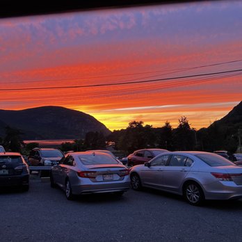 Riverview Restaurant - View - Cars parked in a lot during sunset, with a scenic mountain view and a vibrant, colorful sky overhead. - New American Near Me - Cold Spring, New York