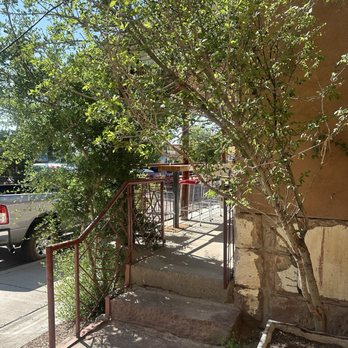 305 Fire - An outdoor patio with a tree, metal railing, and concrete steps leading to a seating area with bar stools. - Pizza Near Me - Gallup, New Mexico