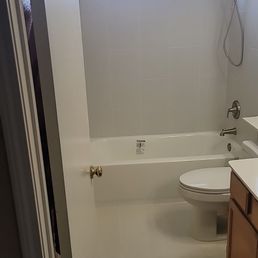 This room was gutted from water damage. It is now beautiful thanks to Joseph - A bathroom features a bathtub with a showerhead, a toilet, and a small window near the ceiling for ventilation.