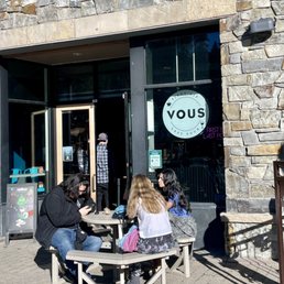 a group of people sitting at a table outside a store a group of people sitting at a table outside a store