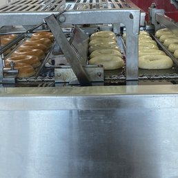 Freshly fried glazed donuts on the conveyer Freshly fried glazed donuts on the conveyer