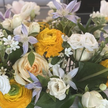 Fleurelity - A floral arrangement featuring white, yellow, and purple flowers, including roses, ranunculus, and other seasonal blooms, with green foliage. - Florists Near Me - Oakton, Virginia