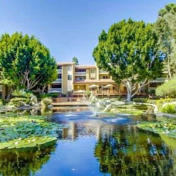 The Plaza Condominiums - Relaxing community pond with fountain and tables with shade umbrellas. - Condominiums Near Me - San Diego, California The Plaza Condominiums - Relaxing community pond with fountain and tables with shade umbrellas. - Condominiums Near Me - San Diego, California