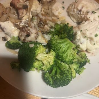 Applebee's Grill + Bar - Bourbon Street Steak* - A white plate holds steamed broccoli florets, creamy mashed potatoes garnished with herbs, and a portion of sautéed mushrooms with onions. The dish appears to be served in a restaurant setting, with the food arranged in separate sections on the plate. - Sports Bars Near Me - Turlock, California