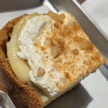 Mac's Local Eats - Banana pudding cheesecake - A slice of banana pudding cheesecake topped with whipped cream and crushed cookie crumbs, served in a metal tray at Mac's Local Eats. - American Near Me - St Louis, Missouri
