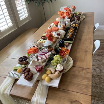 Brie & Beyond - a long table with fruit and flowers - Caterers Near Me