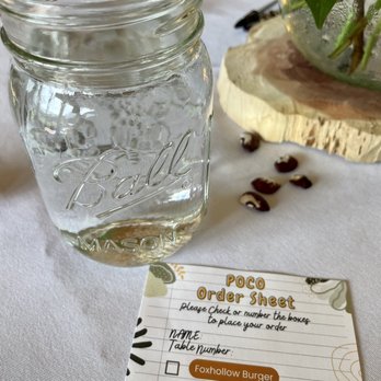 POCO - a jar of water and a notepad on a table - Pop-Up Restaurants Near Me POCO - a jar of water and a notepad on a table - Pop-Up Restaurants Near Me