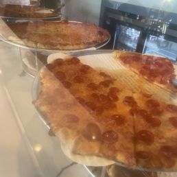 NY style pizza slices on display, ready to reheat. Deliciously greasy. NY style pizza slices on display, ready to reheat. Deliciously greasy.