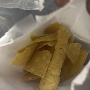 La Catrina - Chips - A handful of yellow tortilla chips are inside a white paper bag, with some chips overlapping each other. - Mexican Near Me - Newburgh, Indiana