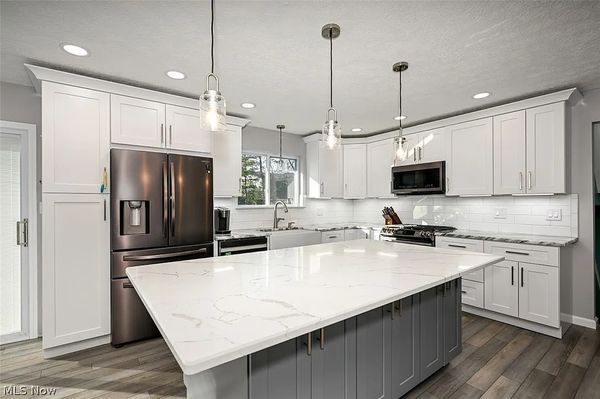 North Olmsted Kitchen Remodel - This remodel was a rather large production, I removed the old walls, as they closed the kitchen off from the other common areas. Once the walls were out, it just opened right up for that beautiful island to be showcased. Lighting was minimal, to non existent on the entire first floor, which led to recessed lighting being installed throughout, as well as pendants or the sink and island and under cabinet lighting to boot. The island added much appreciated storage space, along with the large pantry. There was a large window on back wall, I replaced that with a 6’ sliding patio door, to give access to deck in the backyard. Before the remodel there were multiple types(3 types) of flooring on the 1st floor, I installed LVP(luxury vinyl plank) throughout the 1st floor and down into lower area of this North Olmsted split level home.