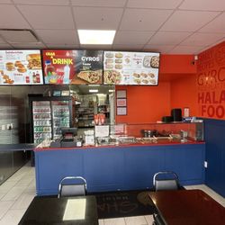 Shah’s Halal Food - The menu board and the interior of the restaurant, which includes a few tables.