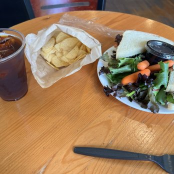 Numinous Coffee Roasters - Chicken sandwich with greens and a side of chips. Ice coffee with vanilla flavoring. - Coffee & Tea Near Me - Marble Falls, Texas