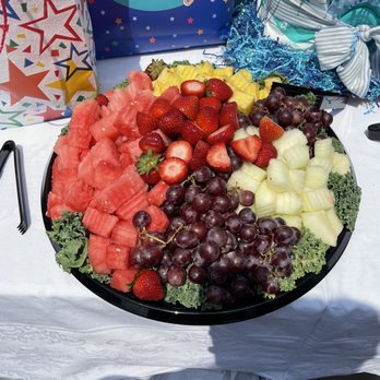 Catering By Jotal - Beautiful Large fruit plate - A large fruit platter featuring watermelon, strawberries, red and green grapes, honeydew, and pineapple, arranged on a black tray. - Caterers Near Me - Worth, Illinois