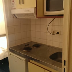 Appart'City Blois - Kitchenette including microwave, mini-fridge, cupboards containing plates, cups, and bowls