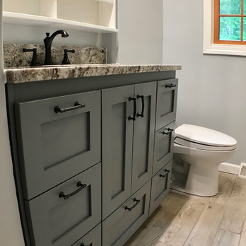 Bicca Carpentry and Remodeling - a bathroom with gray cabinets and a white toilet - General Contractors Near Me - Orlando, Florida Bicca Carpentry and Remodeling - a bathroom with gray cabinets and a white toilet - General Contractors Near Me - Orlando, Florida