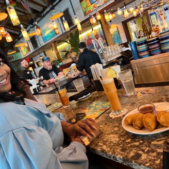 Bahama Breeze - a woman sitting at a bar with a plate of food - Latin American Near Me - Charleston, South Carolina Bahama Breeze - a woman sitting at a bar with a plate of food - Latin American Near Me - Charleston, South Carolina