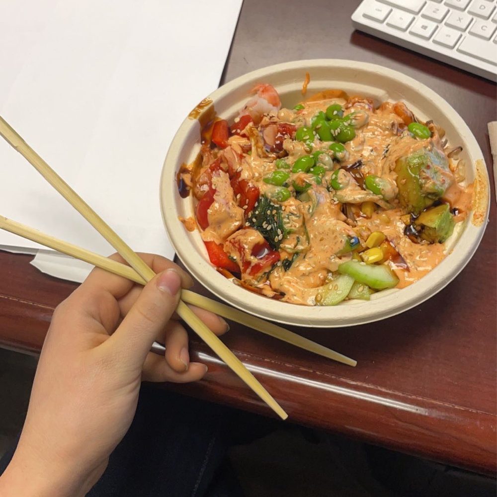 a person holding chopsticks over a bowl of food a person holding chopsticks over a bowl of food