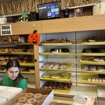 Allegretti's Bakery - Fresh breads, cakes and pies - Bakery display case with assorted breads, pastries, and cakes, with a young girl working behind the counter in a bakery shop. - Bakeries Near Me - Norridge, Illinois