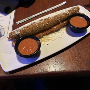 Jasper's - Fried breaded appetizer with shredded cheese on top, accompanied by two small black cups of dipping sauce, served on a white rectangular plate. - American Near Me - Upper Marlboro, Maryland