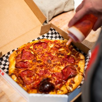 Pizzamoto - a person putting pepperoni on a pepperoni pizza - Pizza Near Me - Tofino, British Columbia