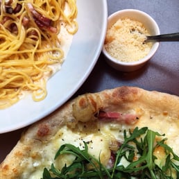 Pasta carbonara and cream-based pizza with bacon and arugula.