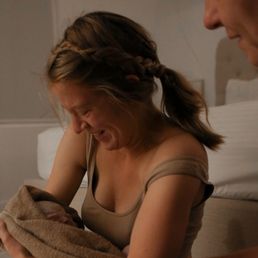 Richelle the midwife looks over mom as she holds her new baby. Richelle the midwife looks over mom as she holds her new baby.