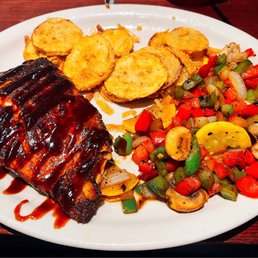 Grilled salmon with sriracha bourbon sauce, sautéed vegetables, and fried squash. Grilled salmon with sriracha bourbon sauce, sautéed vegetables, and fried squash.