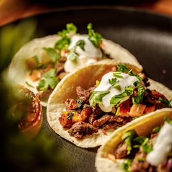 Playoffs Sports Lounge - Warm corn tortillas filled with seasoned meat, topped with fresh cilantro, onions, and house sauce.