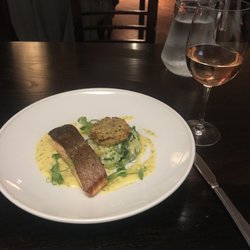 Sous Le Nez En Ville - Pan-roasted salmon fillet with crispy skin, plated with creamy yellow Fennel Hollandaise sauce, a few sprigs of watercress, and side dishes