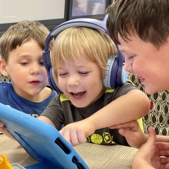 Chick-fil-A - Henry and two other boys crowd around a tablet, one still wearing headphones he's stopped listening to. None are actually eating their food. - Salad Near Me - Taylors, South Carolina