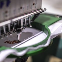 Printology Screen Printing and Embroidery - An embroidery machine stitching out a custom logo onto apparel.