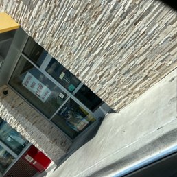 Front door with "lobby closed" sign - The image shows the exterior of a commercial building with a glass door and a stone facade. A sign on the door advertises starting wages of $14.00 an hour. The sidewalk and part of the building's exterior are visible, with no additional signage or identifying features.
