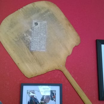 Thad's Place - a man standing in front of a wall with pictures and a wooden paddle - Pizza Near Me - Montgomery, Pennsylvania Thad's Place - a man standing in front of a wall with pictures and a wooden paddle - Pizza Near Me - Montgomery, Pennsylvania