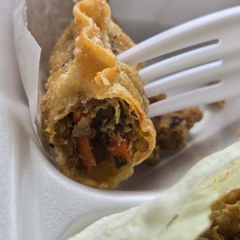Rice Box & Boba  - Fried dumpling - Close-up of a fried dumpling with a crispy exterior, showing its vegetable and meat filling inside, served in a takeout container. - Laotian Near Me - Albuquerque, New Mexico