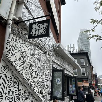 Textbook - a woman sitting on a bench in front of a graffiti covered building - Coffee & Tea Near Me - Brooklyn, New York