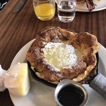 Tilikum Place Cafe - Classic Dutch Baby: topped with lemon and powdered sugar. (TPC Breakfast Plate in the background). - New American Near Me - Seattle, Washington Tilikum Place Cafe - Classic Dutch Baby: topped with lemon and powdered sugar. (TPC Breakfast Plate in the background). - New American Near Me - Seattle, Washington